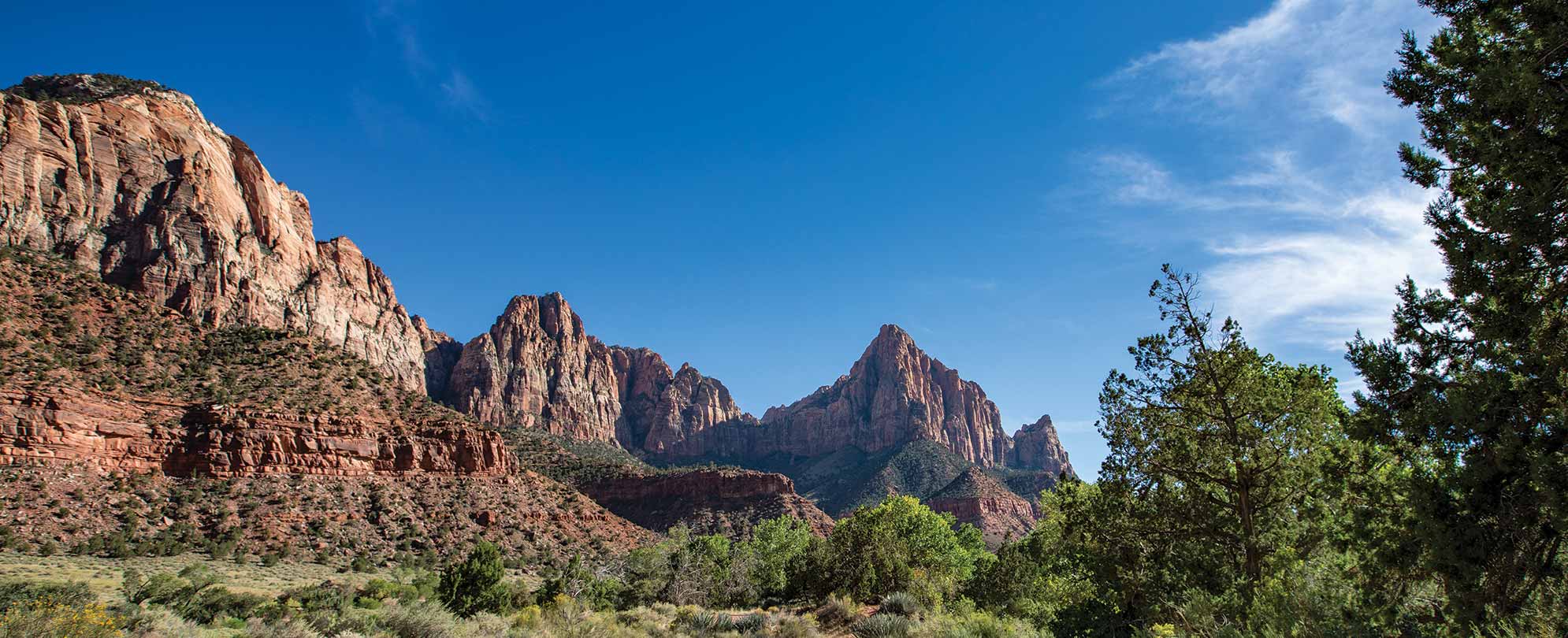 Crimson rocks form the tall cliff walls of a canyon at Zion National Park in Utah