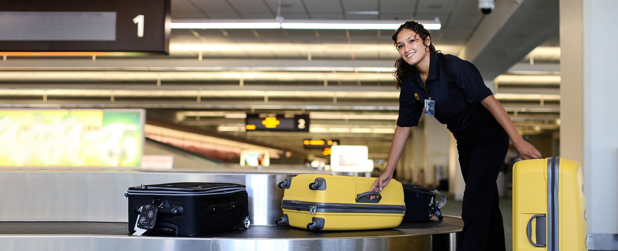 Woman is picking up luggage from the baggage claim area at airport.