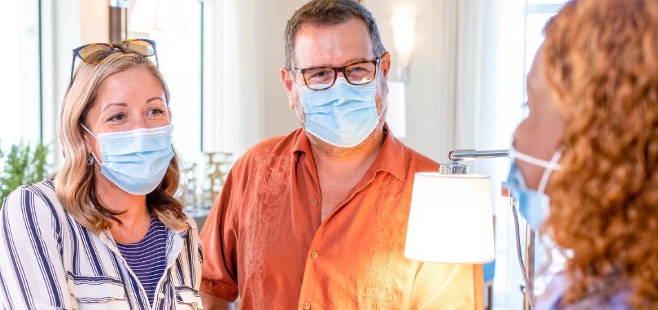 A couple wearing blue medical masks speak to a female employee at a Margaritaville Vacation Club resort during COVID-19.