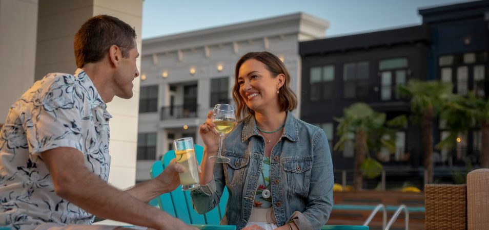 Man and woman sit in adirondek chairs each holding a drink while staying at a Margaritaville Vacation Club resort.