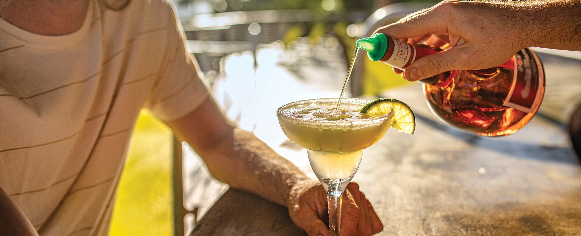 Bartender pouring liquor into a green frozen margarita at a Margaritaville Vacation Club resort bar.