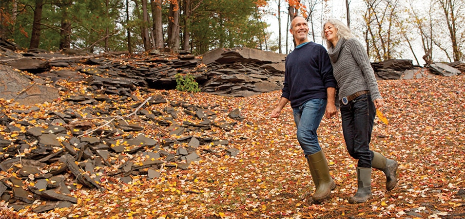 An older couple hikes through forest on an autumn day.