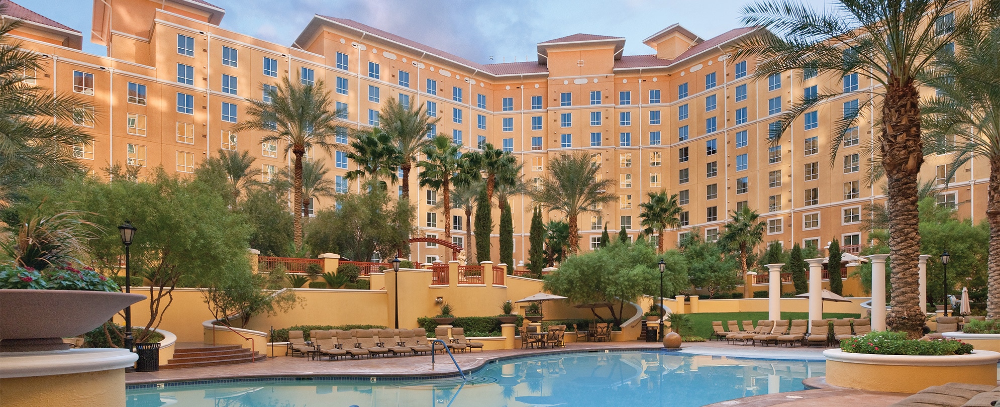 An outdoor pool surrounded by palm trees in front of Club Wyndham Grand Desert, a timeshare resort in Las Vegas, Nevada.