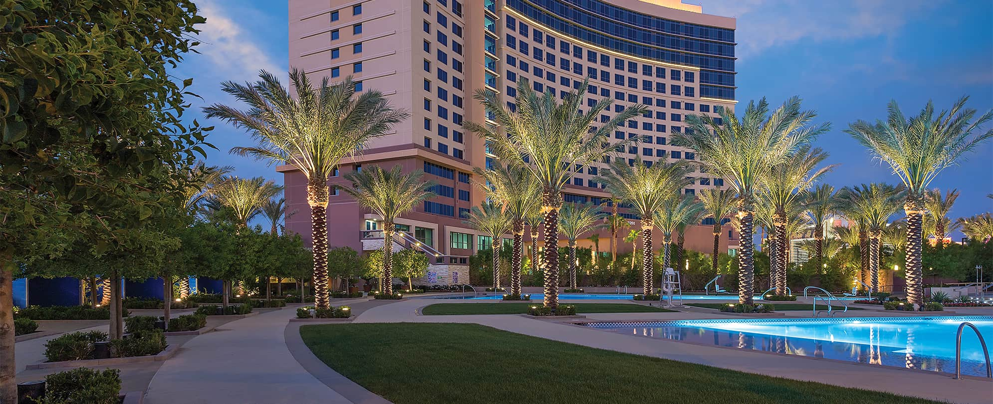 Pool and palm trees lit up at night at Margaritaville Vacation Club by Wyndham - Desert Blue in Las Vegas, NV.